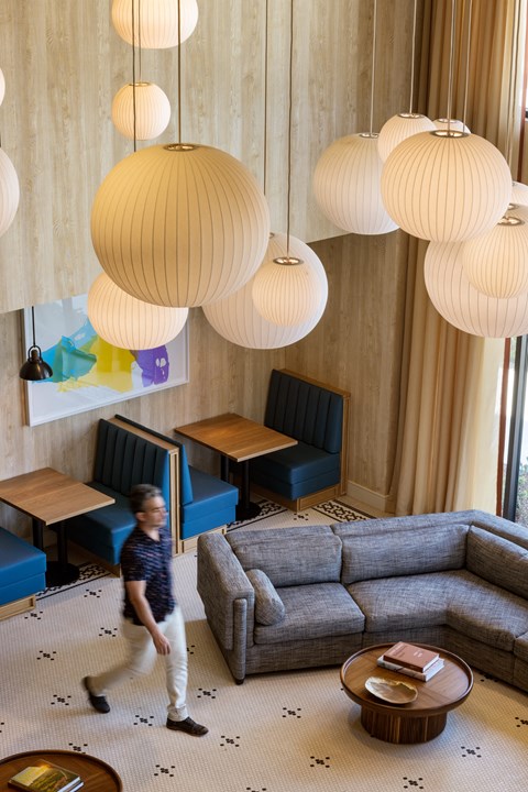 a young boy walking through a living room with lamps hanging from the ceiling