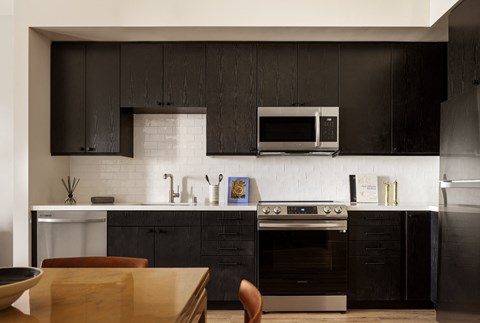 a kitchen with black cabinets and a stove and a microwave