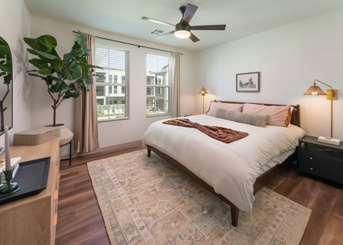 A bedroom with a large bed, a ceiling fan, and a window with curtains.
