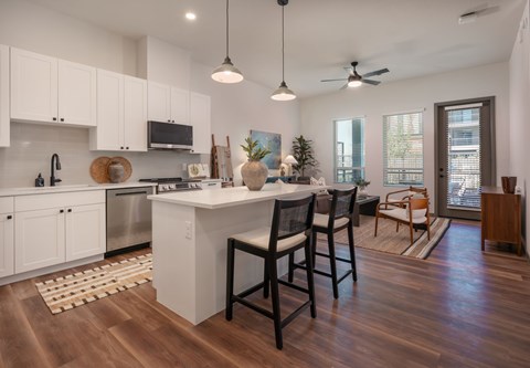 A kitchen with white cabinets and a wooden floor.