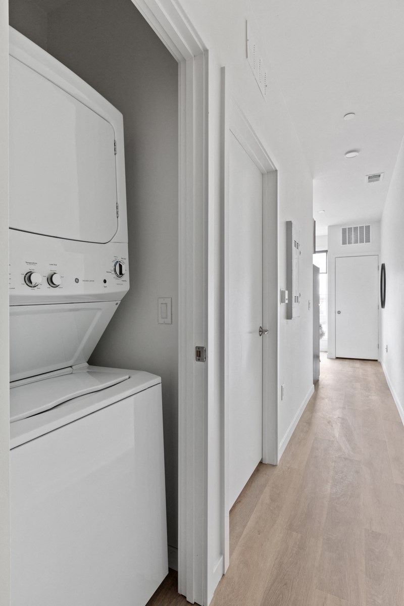 a white washer and dryer sit in a white room with a wood floor