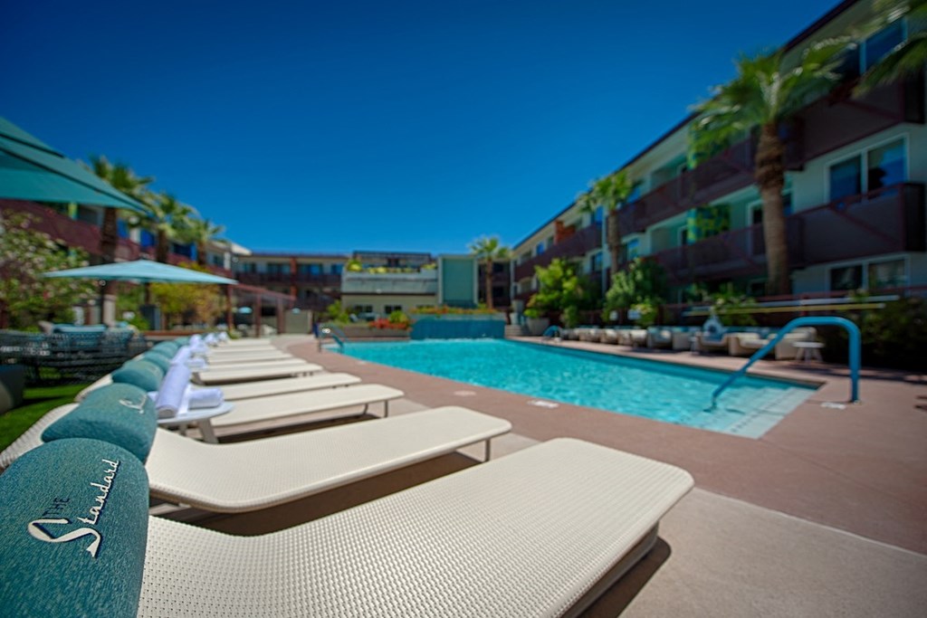 A pool with sun loungers and a blue sky in the background.