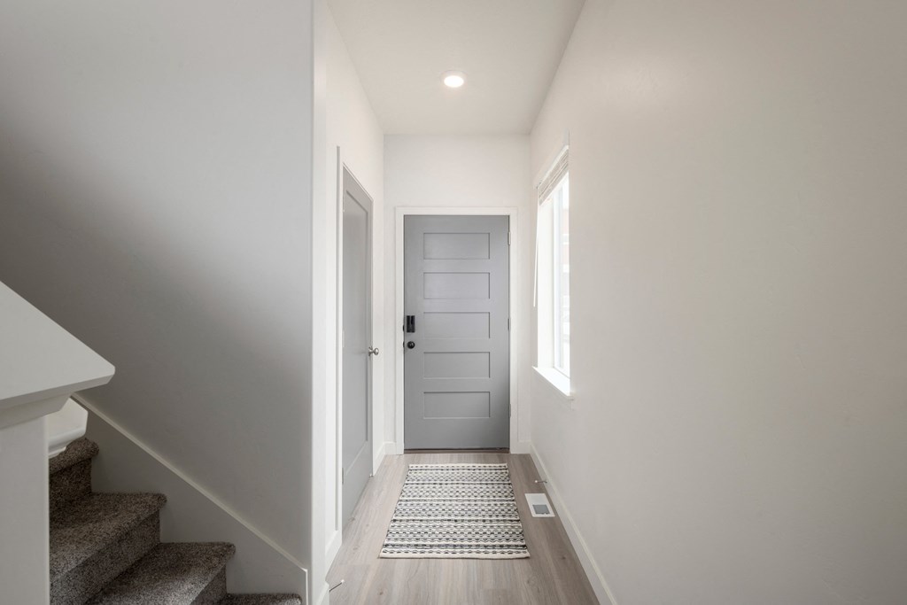 a hallway with stairs and a door to a house