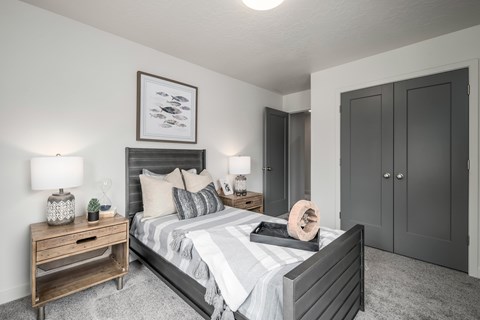 A bedroom with a large bed, a nightstand with a lamp, and a framed picture on the wall.