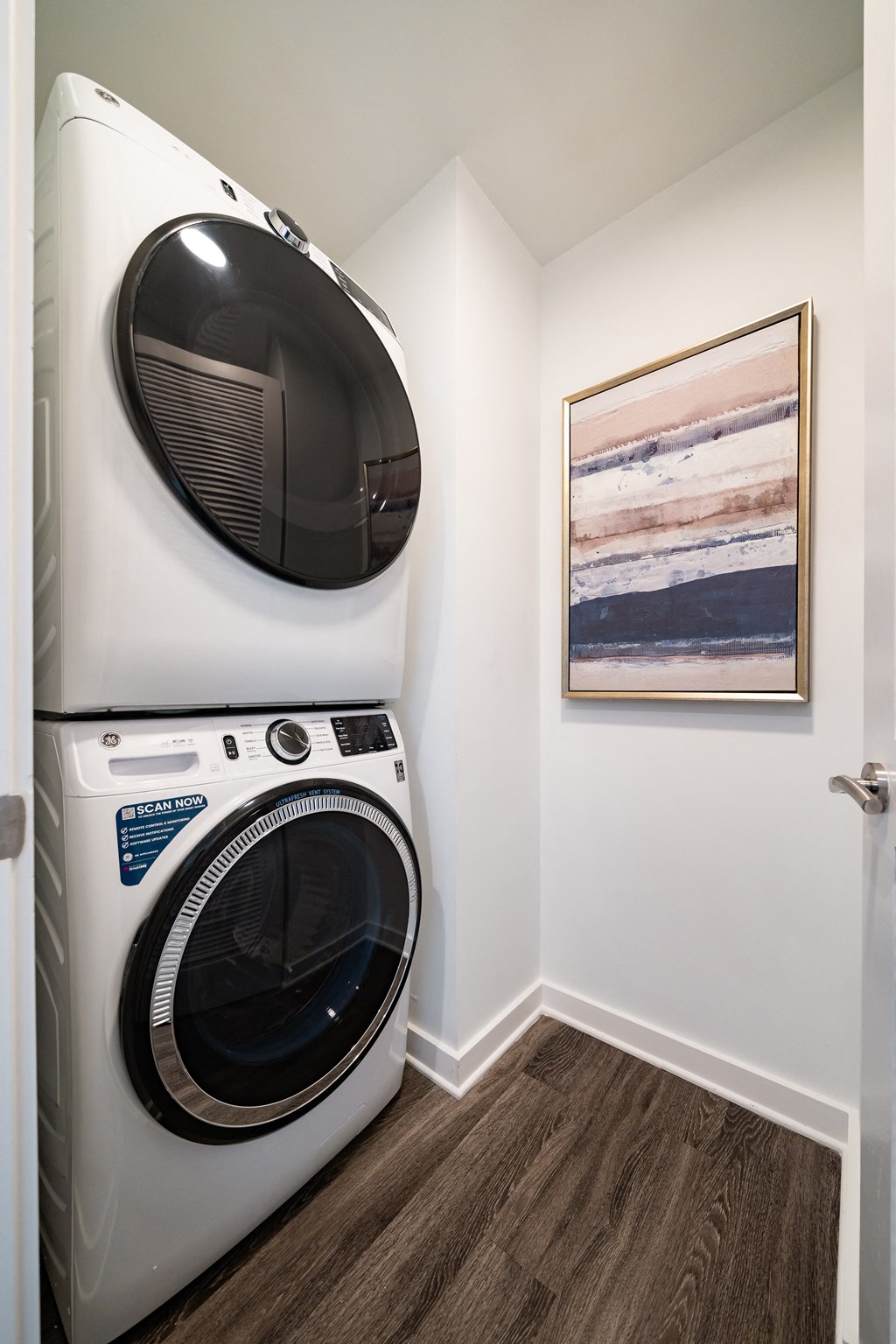 a washer and dryer in a laundry room with a painting on the wall