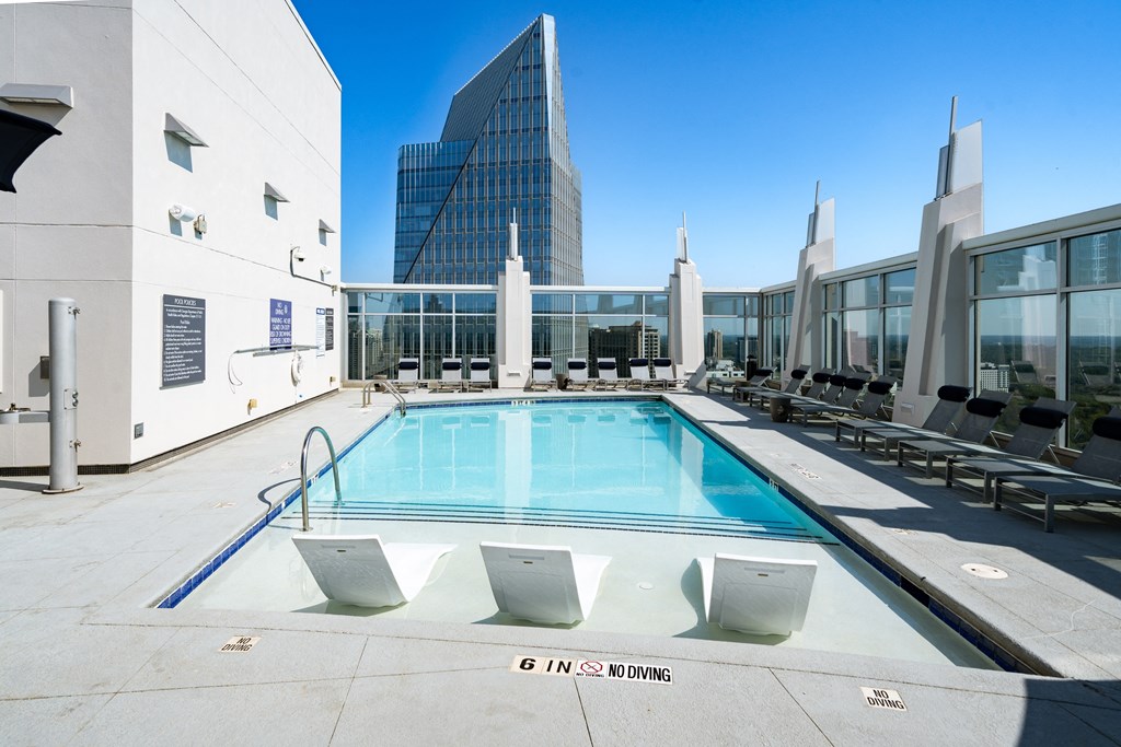 a pool on the rooftop of a building with a skyscraper in the background