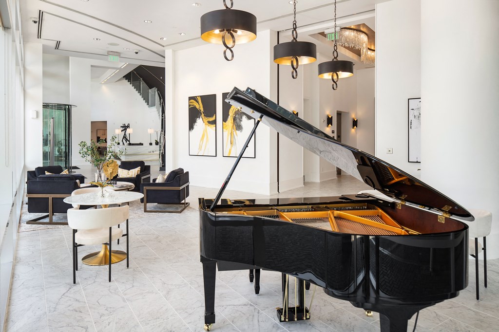 a large black piano in a living room with chairs and a table