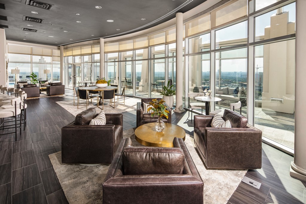 a living room with leather chairs and tables and large windows