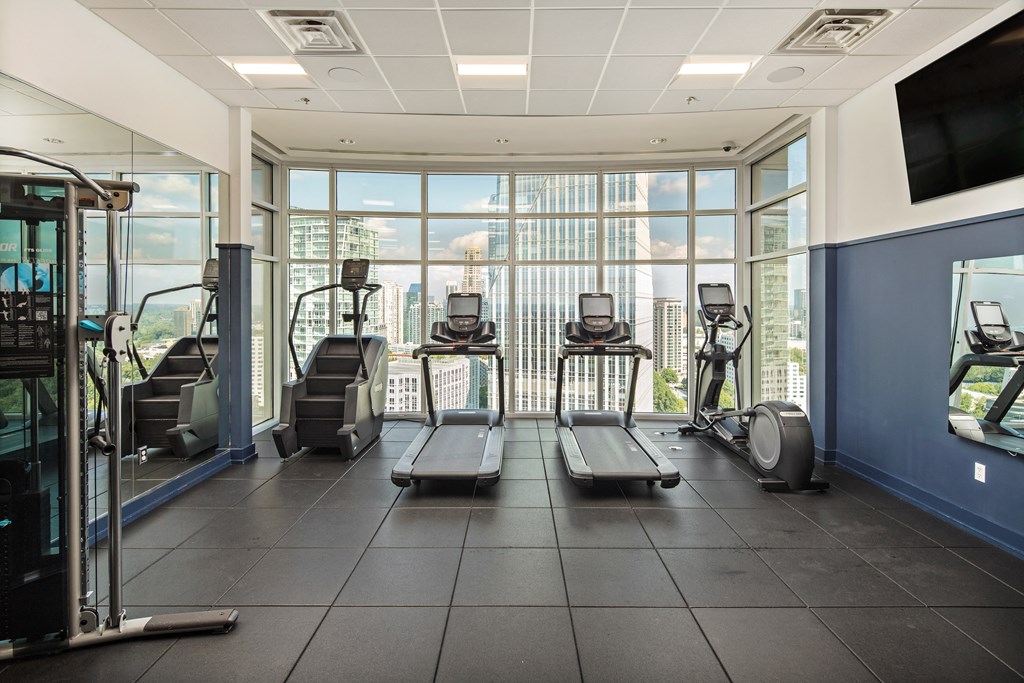 a gym with cardio machines and a view of the city