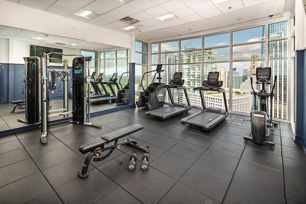 a gym with cardio equipment and a view of the city