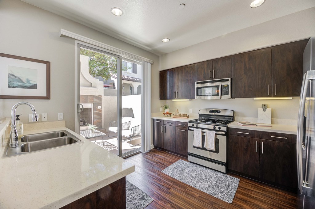 a kitchen with a sink and stove and a door to a patio
