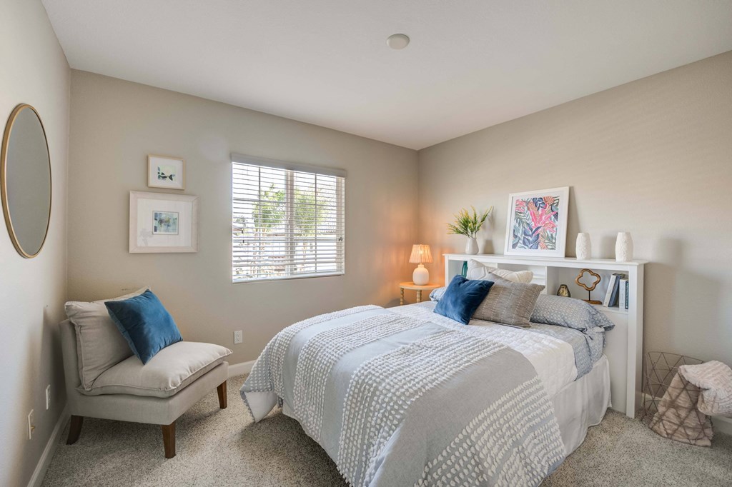 a bedroom with a bed and a chair and a window