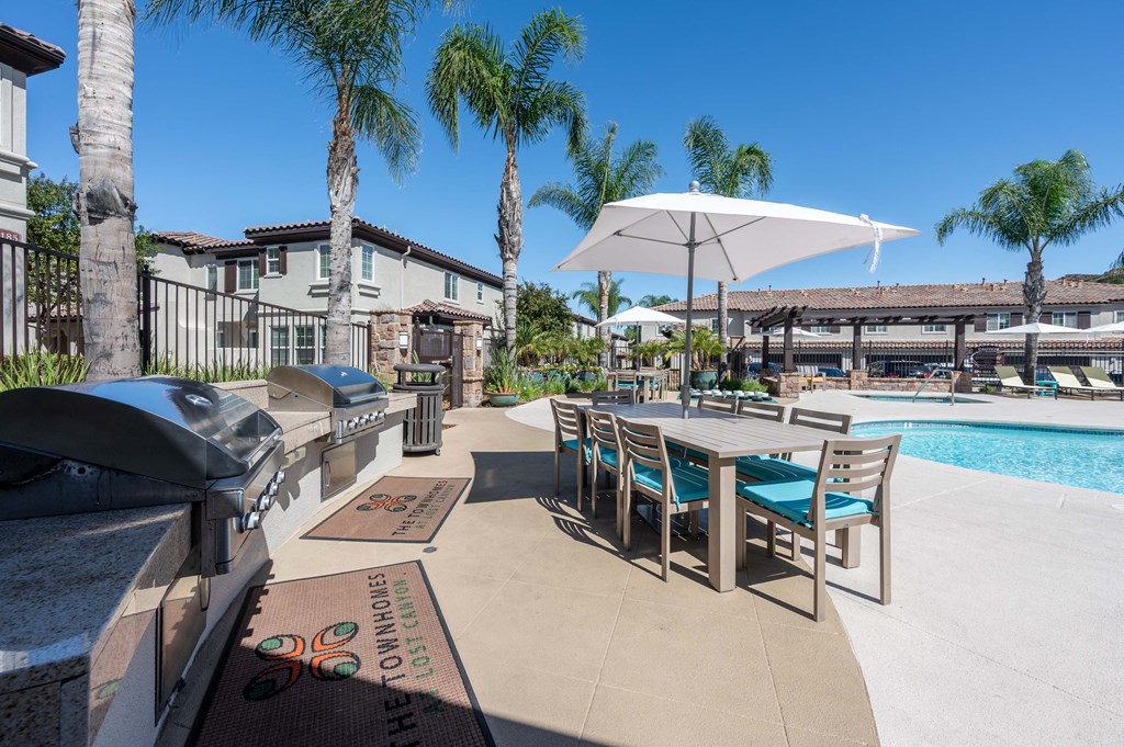 an outdoor grill area with a table and chairs