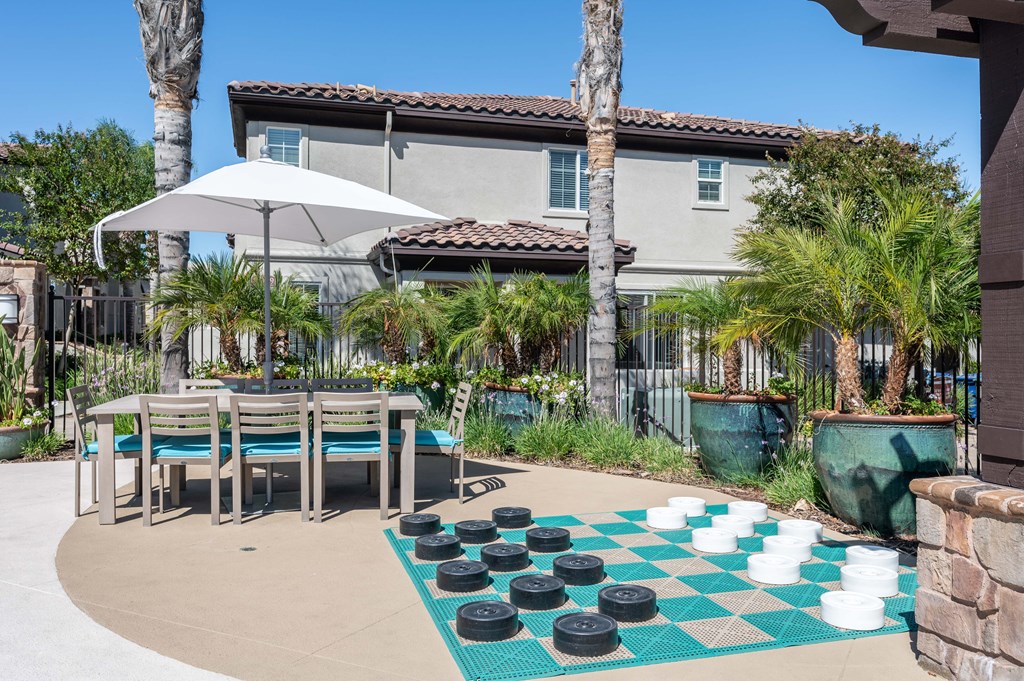 an outdoor checkers game with a table and chairs
