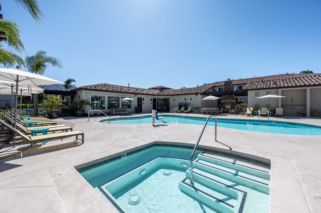 a swimming pool and spa with chairs and umbrellas