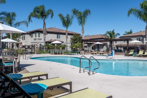 a gated swimming pool with chairs and umbrellas
