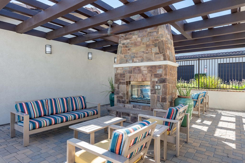 a patio with a fireplace and chairs and tables