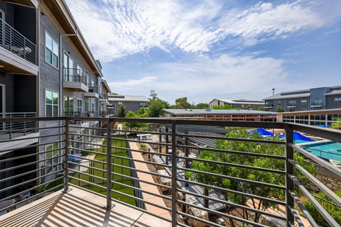 A balcony overlooks a pool and greenery.
