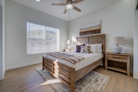 A bedroom with a bed, nightstand, and window with blinds.