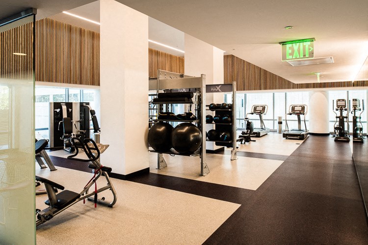 a large fitness room with exercise equipment and a exit sign