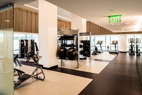 a large fitness room with exercise equipment and a exit sign