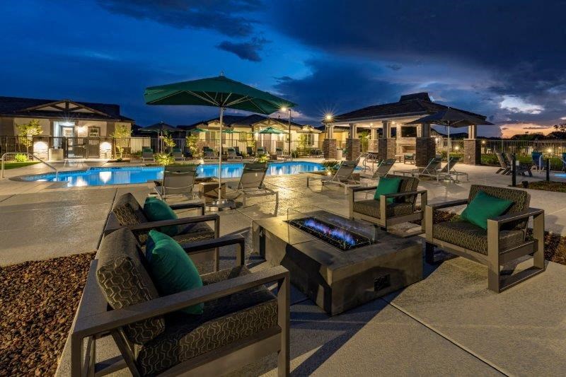 a pool with chairs and umbrellas at night