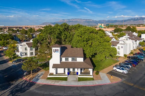 an aerial view of a large white house with a brown roof and a parking lot