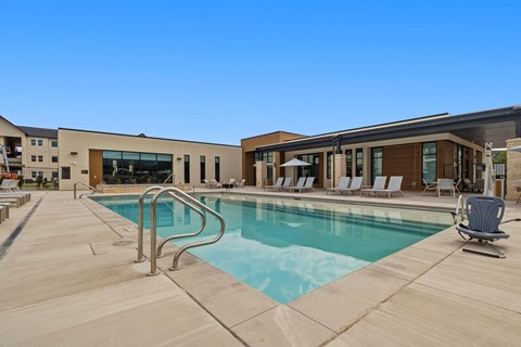 A large swimming pool with a metal ladder and a few chairs around it.