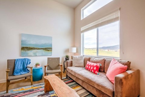A living room with a brown couch, a blue chair, and a painting on the wall.