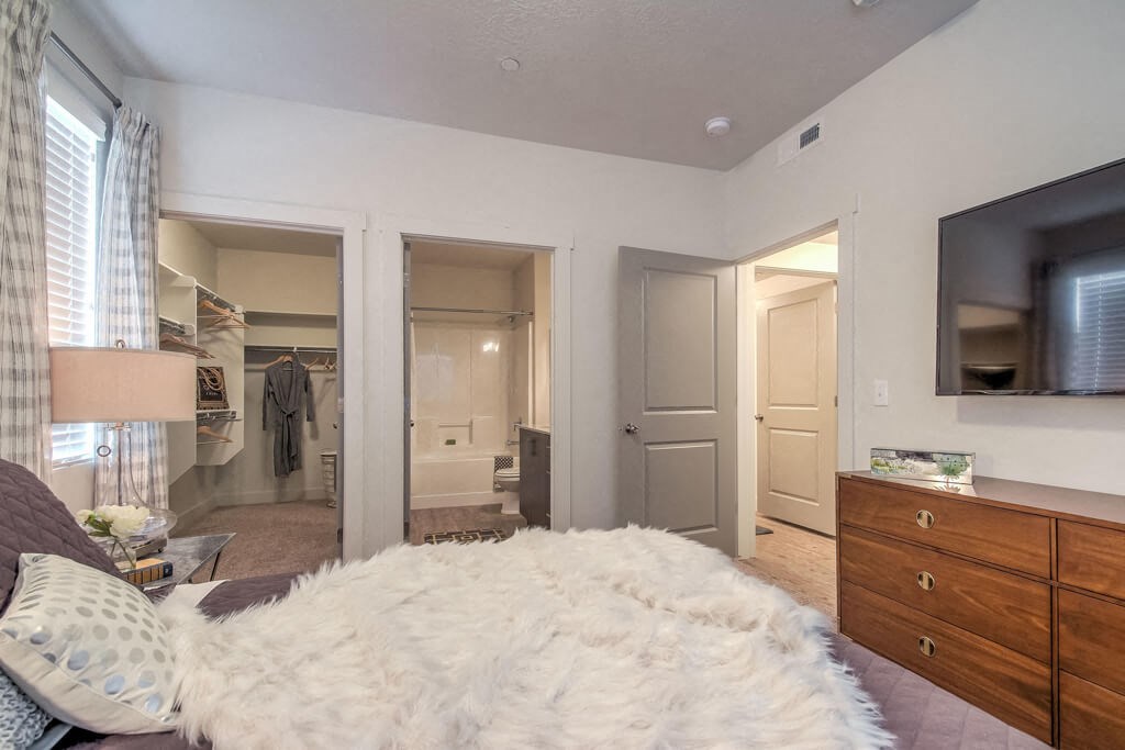 furnished model bedroom with walk-in closet and attached bathroom