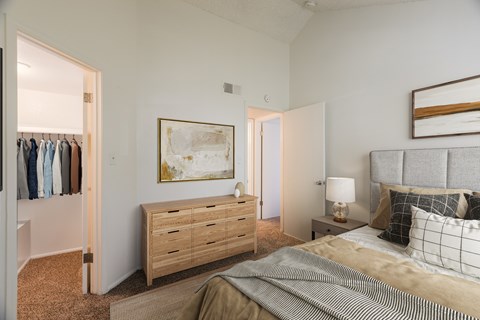 A bedroom with a bed, nightstand, and a painting on the wall.