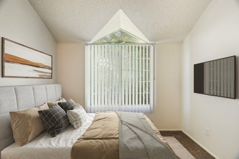 A bedroom with a bed, pillows, and a painting on the wall.