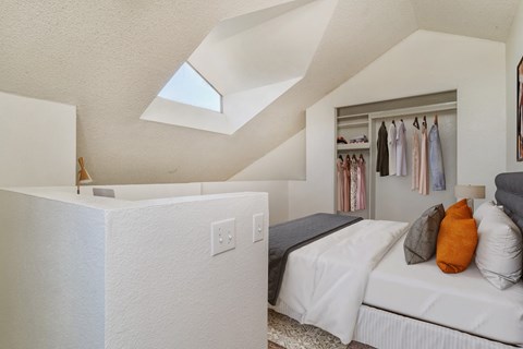 two beds in a room with a closet and a skylight