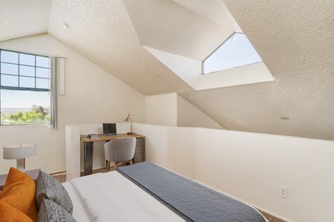 a bedroom with a bed and a desk with a window