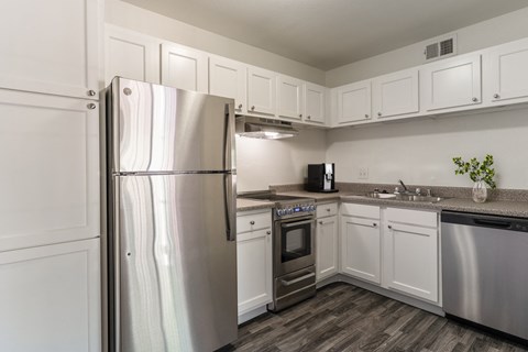 an empty kitchen with stainless steel appliances and white cabinets