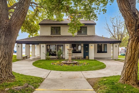 a house with a fountain in the center of a circle of grass