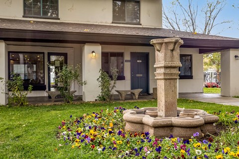 a garden with a stone fountain in front of a house
