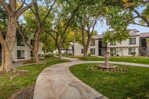 a sidewalk with trees and apartments in the background