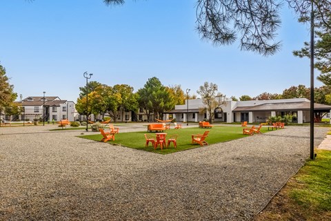 a park with orange tables and chairs on the grass