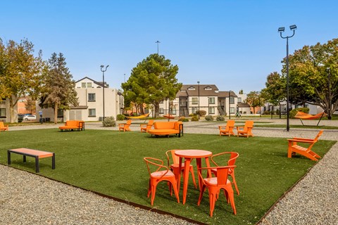 an outdoor seating area with tables and chairs on the grass