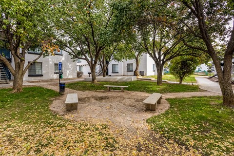 a park with benches and trees in front of a building
