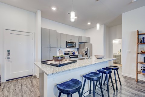 A kitchen with a white counter and blue stools.
