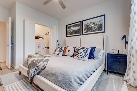A bedroom with a bed, nightstand, and pictures on the wall.