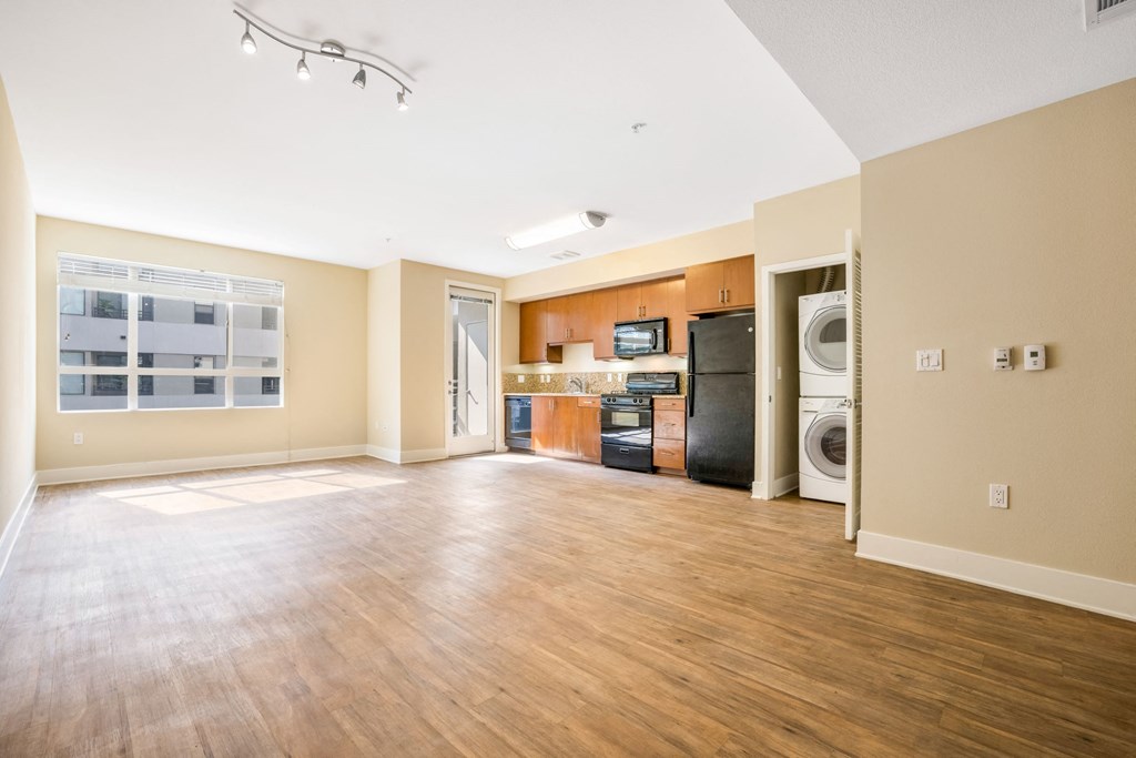 an empty living room with a kitchen and washer and dryer