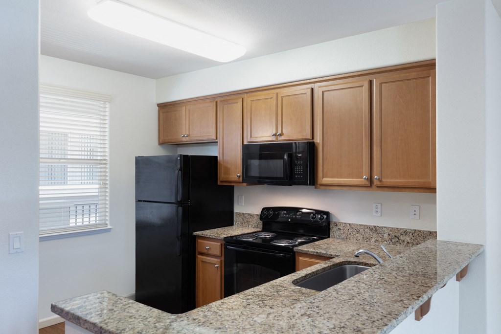 a kitchen with granite countertops and black appliances