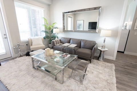 A modern living room with a glass coffee table and a grey sofa.