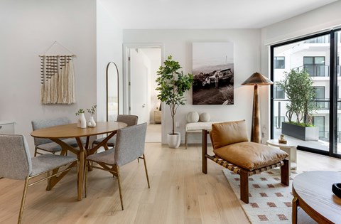 A modern living room with a wooden table and grey chairs.