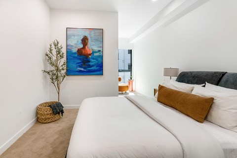 A bedroom with a large bed and a painting of a person in water.
