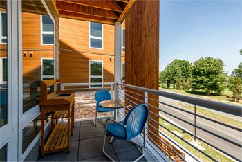 a balcony with two blue chairs and a wooden table
