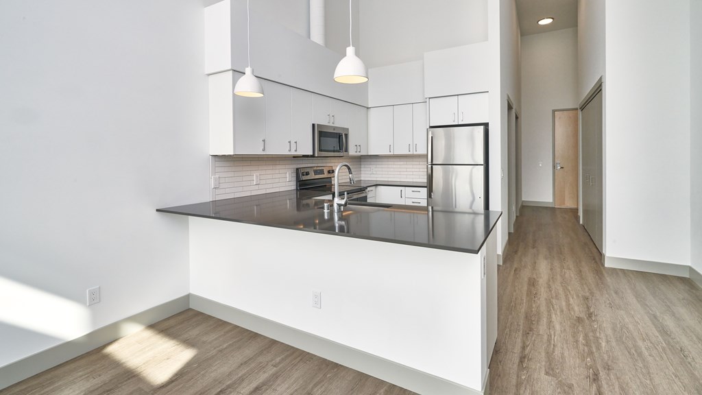 A modern kitchen with white cabinets and a black countertop.